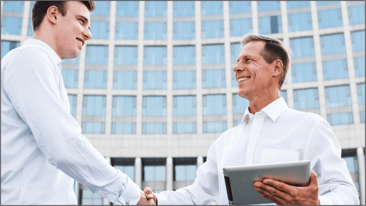 Dois homens sorrindo e apertando as mãos em sinal de parceria