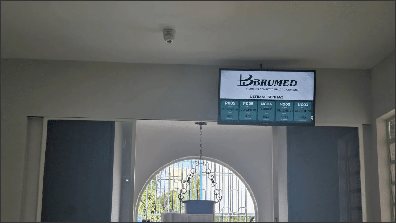 Interior da clínica Brumed com histórico de senhas chamadas exibido em tela